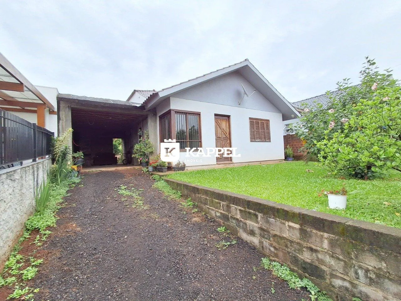 Fachada de uma casa em Lajeado, Brasil, com um pátio gramado e um caminho de terra.