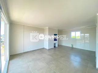 Sala ampla com piso claro e paredes brancas.