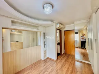 Interior de uma sala com piso de madeira e armários embutidos.