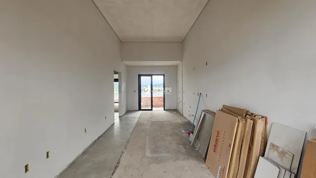 Corredor interno de uma residência com paredes brancas e piso de concreto.