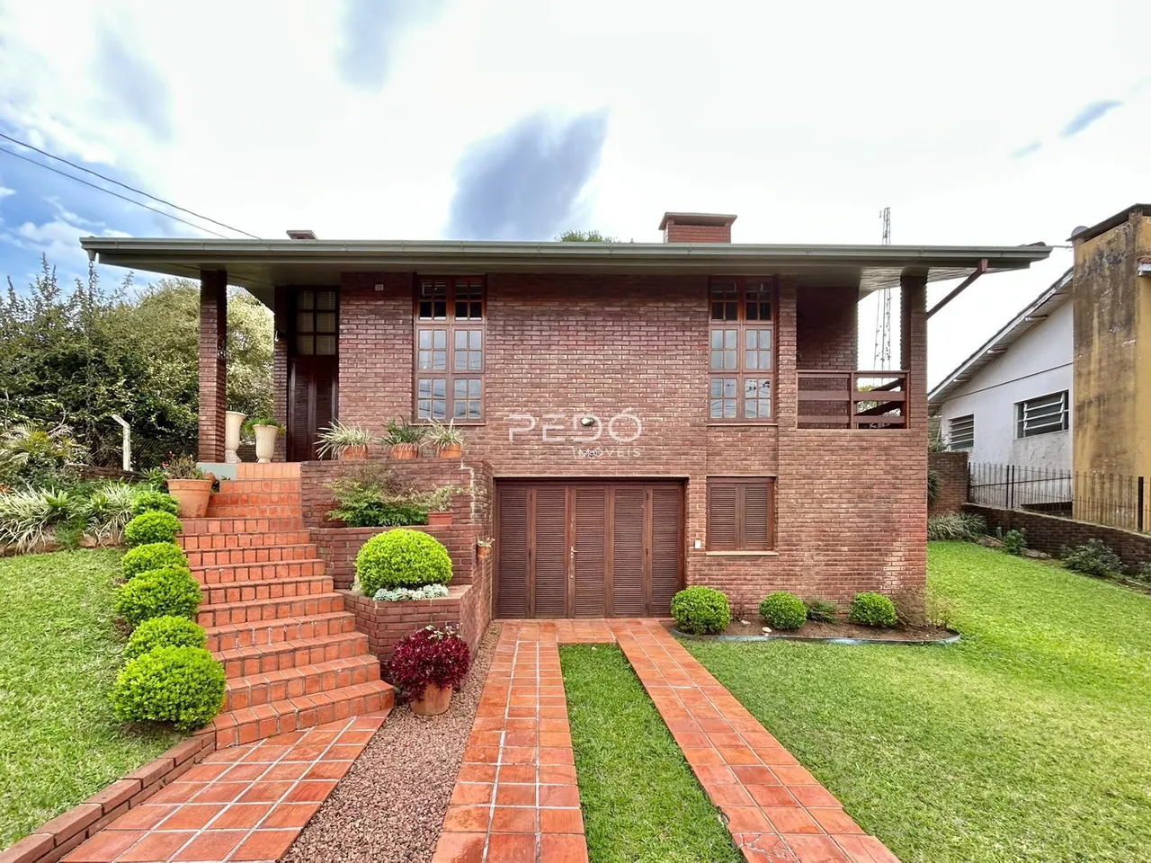 Fachada de uma casa de tijolos com jardim e calçada em Lajeado, Brasil.
