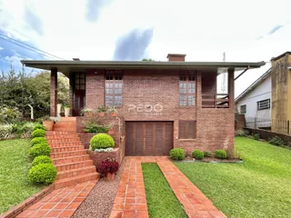 Fachada de uma casa de tijolos com jardim e calçada em Lajeado, Brasil.