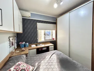 Quarto com cabeceira e armários brancos em um apartamento.