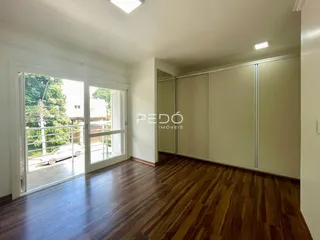Sala de estar com piso de madeira e portas de vidro que dão acesso ao exterior.