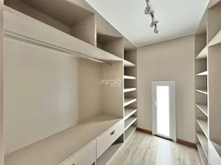 Imagem de um corredor com estantes e armários brancos em um imóvel.