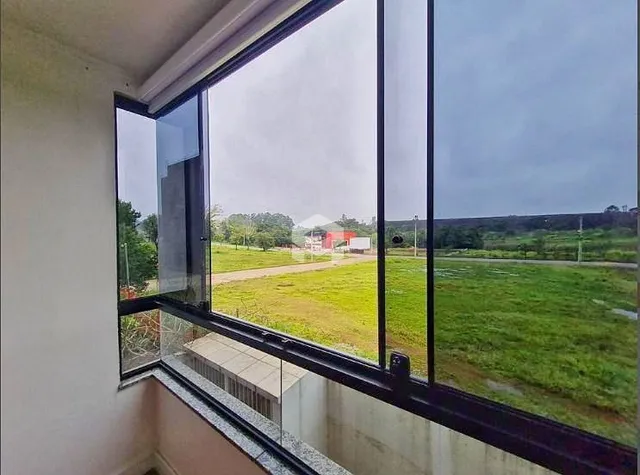 Vista externa de um campo verde através de uma grande janela.