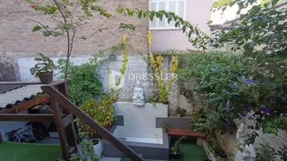 Vista de um jardim com elementos de madeira e vegetação em uma propriedade.