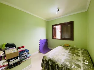 Quarto com parede verde claro e cama na frente da janela.