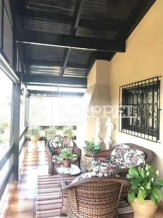 Hall de entrada com piso de madeira e vigas escuras visíveis na área interna.