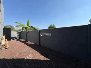 Parede externa de propriedade com paisagismo e muro.