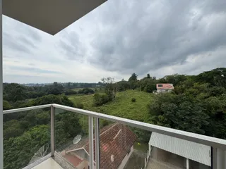 Vista panorâmica de colinas verdes e vegetação densa a partir de uma varanda.