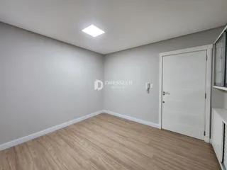 Foto de um cômodo interno com paredes brancas e piso de madeira clara.