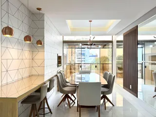 Vista de uma sala de jantar moderna com mesa de vidro e cadeiras em um imóvel no Brasil.