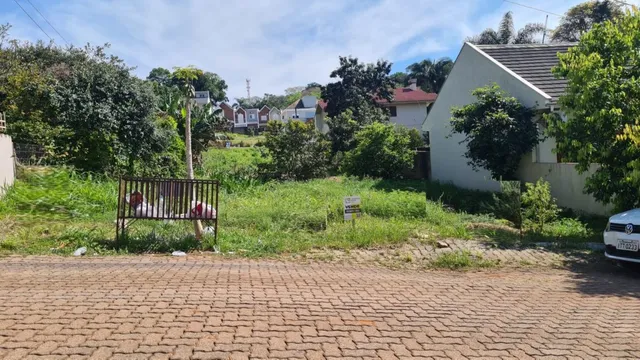 Vista externa de uma propriedade residencial com grama alta no primeiro plano.