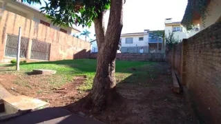 Jardim externo com gramado e muro de tijolos em uma residência.