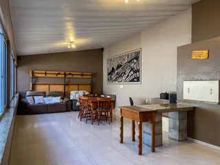 Sala de estar com sofá e mesa de jantar de madeira em um ambiente interno.