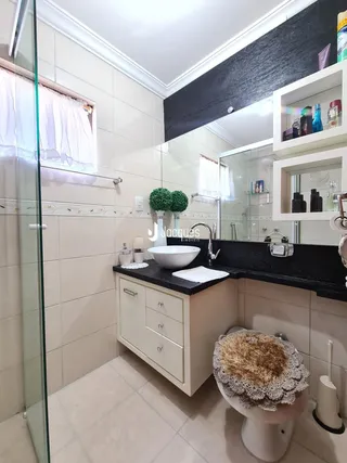 Banheiro com revestimento cerâmico e bancada escura.
