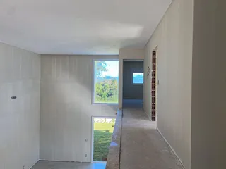 Corredor interno de uma residência com paredes brancas e janelas.
