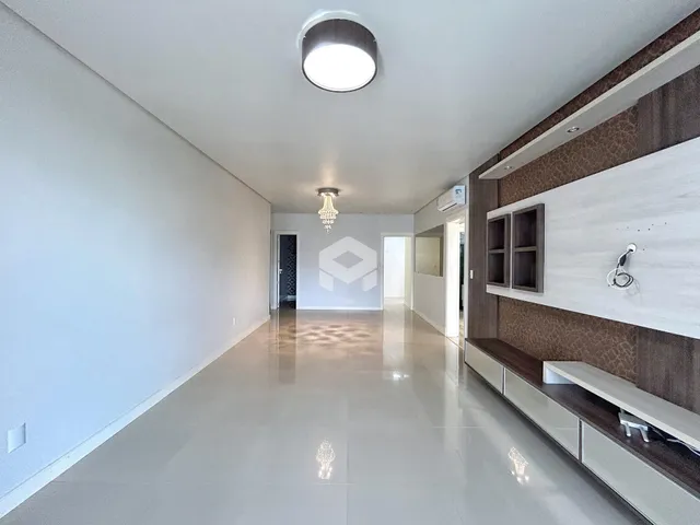 Corredor longo com piso claro e paredes brancas em uma residência.