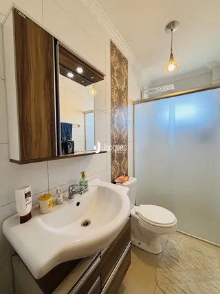 Banheiro com pia, vaso sanitário e box de vidro.