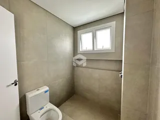 Um banheiro com paredes revestidas de azulejo claro.