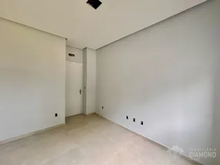 Vista de um corredor interno com paredes brancas e piso de cerâmica.