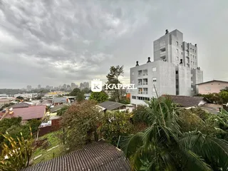 Vista aérea de uma área residencial com edifícios e vegetação no horizonte.