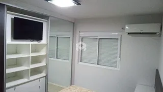 Foto de uma sala de estar com televisão e estantes brancas.