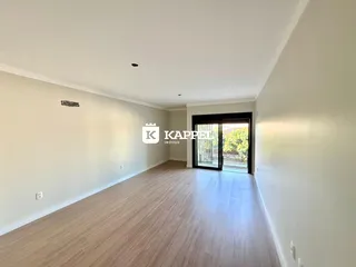 Esta é uma sala de estar ampla com piso de madeira clara e porta de vidro.