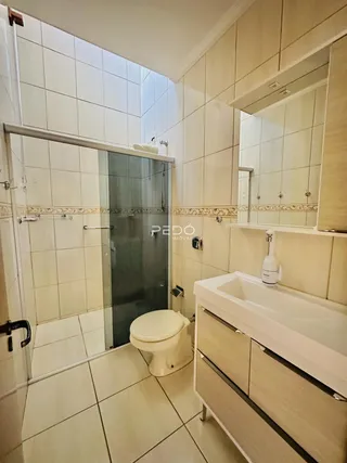 Banheiro com piso de cerâmica e box de vidro.