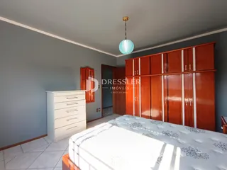 Quarto com armário de madeira e cama em um imóvel no Brasil.