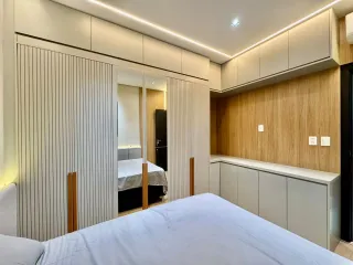 Quarto moderno com cabeceira e armários em madeira clara.
