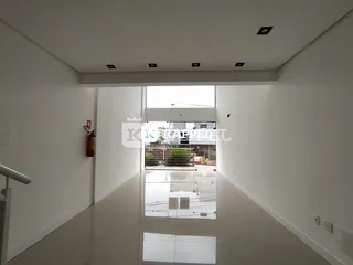 Corredor interno de uma residência com piso claro e paredes brancas.