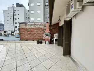 Área externa com piso de cerâmica e parede de tijolos de um imóvel em Lajeado.