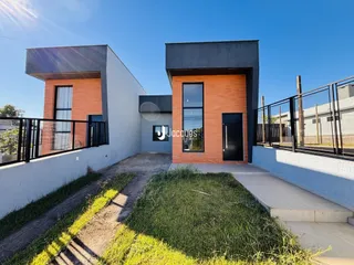 Fachada moderna de uma residência em Lajeado, Brasil, com acabamentos em tijolo aparente e estuque branco.