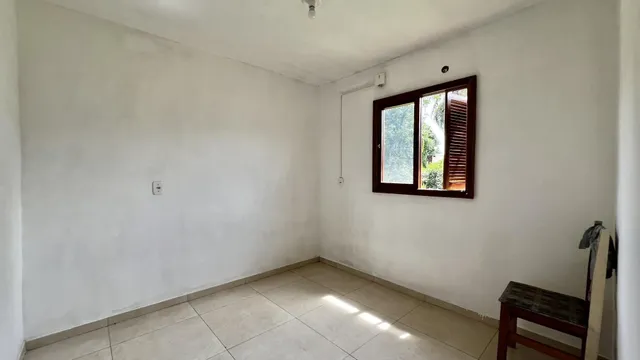 Uma sala de estar com paredes brancas e piso de cerâmica clara.
