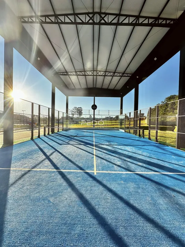Uma quadra esportiva externa coberta com estrutura metálica está visível na propriedade.