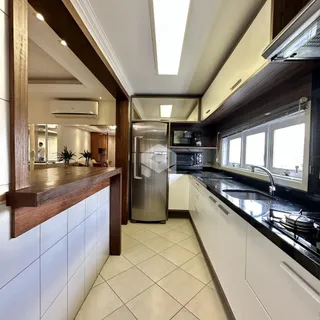 Vista da cozinha com armários e bancadas em madeira e branco.