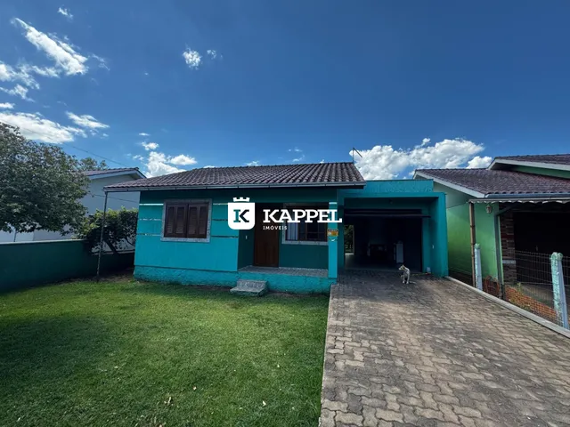Fachada de uma casa com paredes azul-turquesa, jardim e garagem.