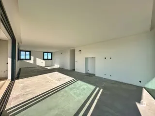Espaço interno amplo com piso de concreto e paredes brancas.