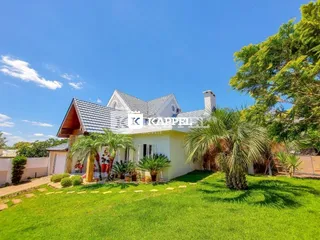 A fachada de uma casa em Lajeado, Brasil, com gramado verde e palmeiras.