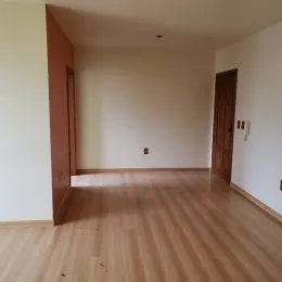 Sala de estar com piso de madeira clara e paredes brancas.