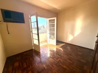 A sala de estar apresenta piso de madeira e acesso a uma varanda.