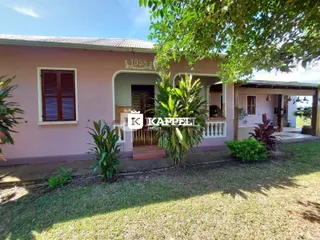 Fachada de uma casa em Lajeado, Brasil, com pintura rosa e vegetação ao redor.