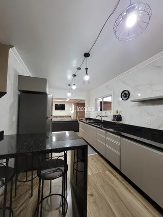 Interior da cozinha com armários e bancadas escuras em um apartamento no Brasil.