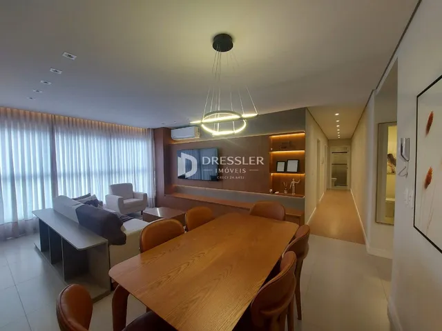Interior de uma sala de jantar com mesa de madeira e estantes na Lajeado.