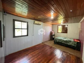 Quarto com piso e teto de madeira no interior da residência.