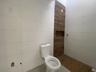 Foto de um banheiro com vaso sanitário branco e paredes brancas.