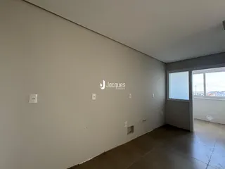 Vista interna de um ambiente com paredes brancas e piso de concreto.