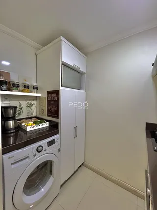 Interior de uma cozinha com armários brancos e máquina de lavar roupa.